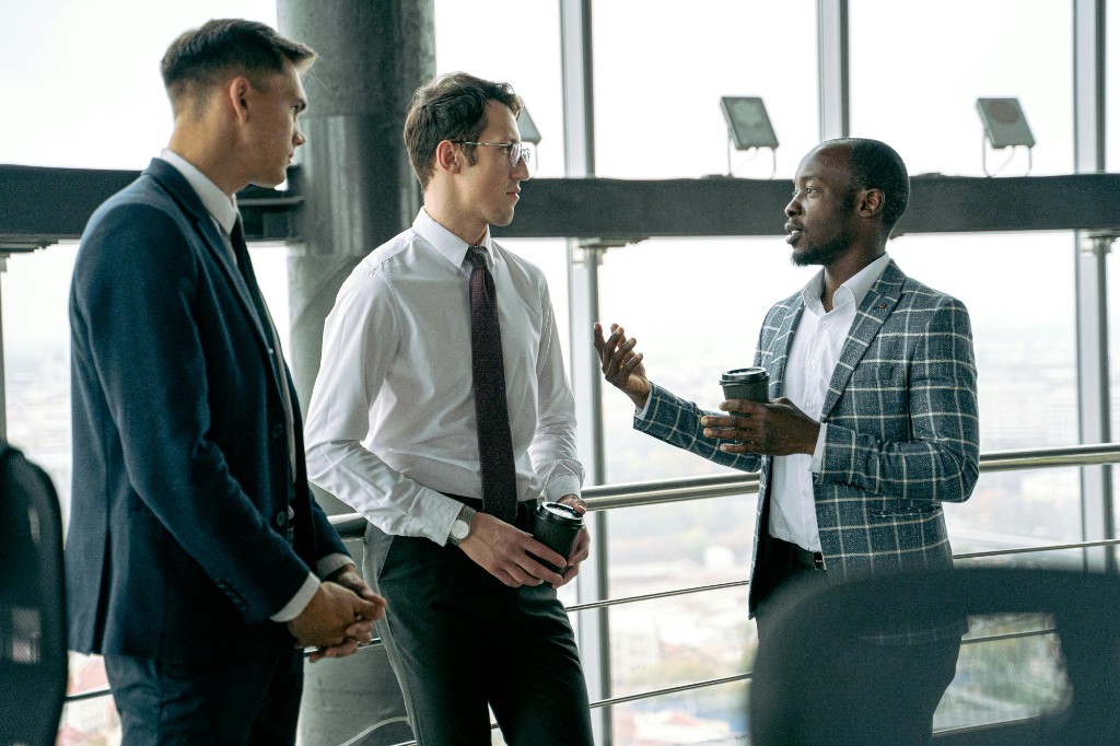 Three professionals in a modern office discussing over coffee — contacts and timeline in CoffeeChat
